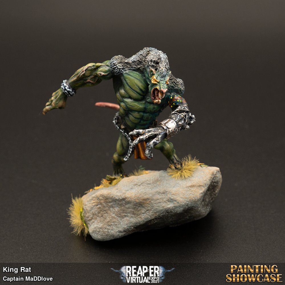 King Rat is a Reaper mini. This creation belongs to Motor City Ray. He won this in one of our many giveaways last year on our channel. The King stands on his rock overlooking his subjects. His rock was obtained from the driveway of our new home that we bought in 2020. He was a co-stream painting session with PaulBWarhammer. Together we painted green skin. The paints used include GW contrast paints, some Reaper silver metallic and he stands in tufts and ground debris from Shadow's Edge.  